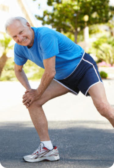 Photo of a senior man in running clothes on an outdoor path doing a lunging stretch.